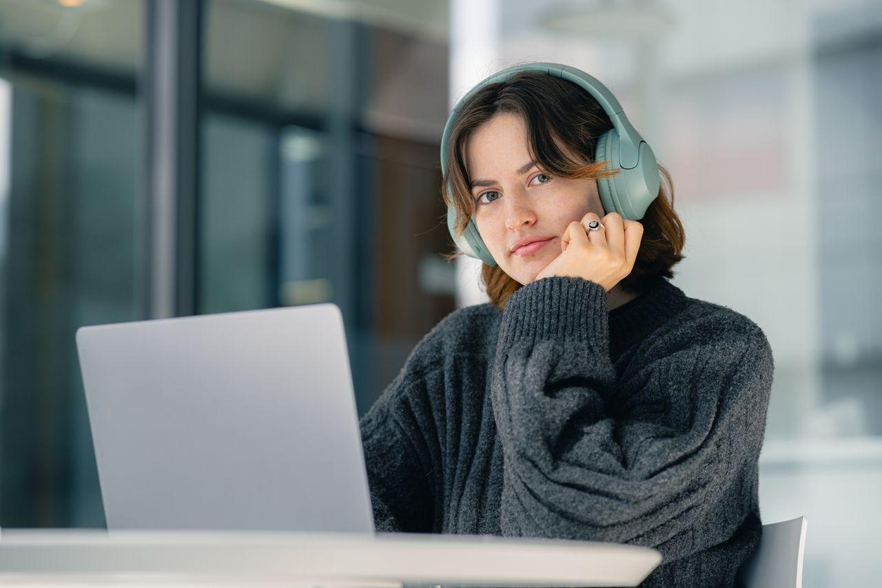 A person with headphones sitting in front of a laptop