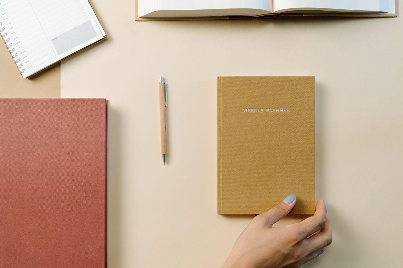 A warm-toned desk with a planner, books and pencils